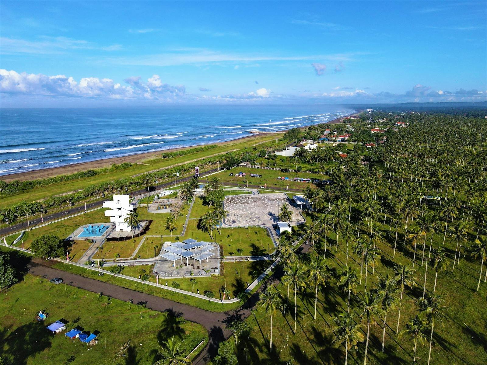 Scenic aerial view of Pangandaran's coastline, resort, and palm groves in West Java, Indonesia.